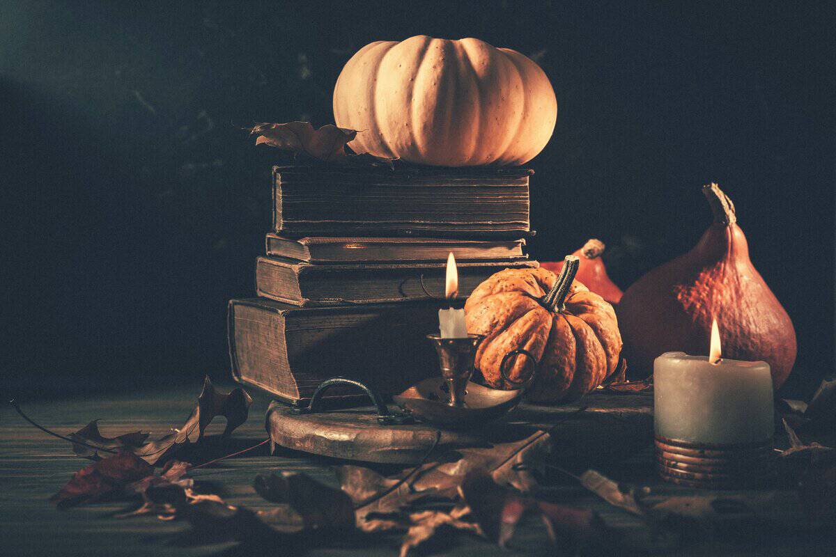 Candlelit still life of pumpkins, gourds, and old books for fall in Denver