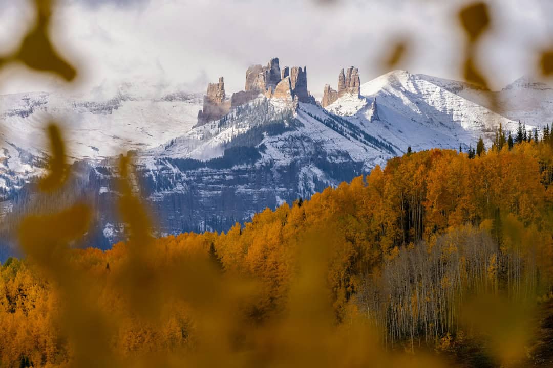 Rock spires and a snow-capped peak framed by golden aspen leaves at Rabbit Ears Pass, Colorado