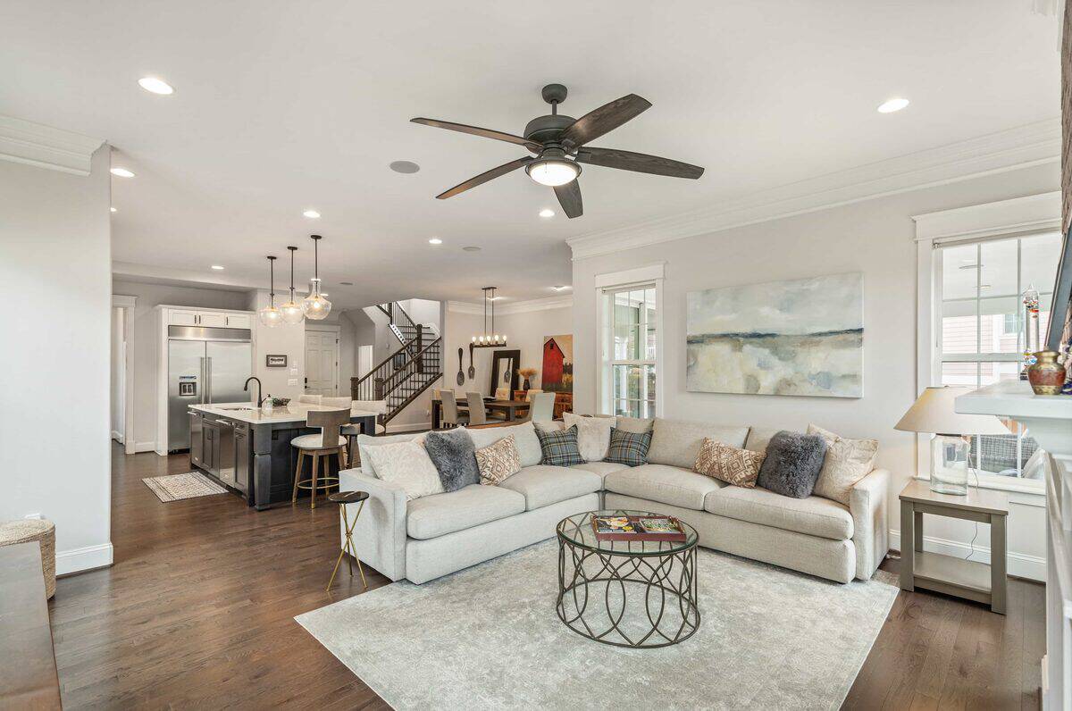 Open-concept living room with gray sectional, kitchen island and staircase at 9859 E 59th North Place, Denver
