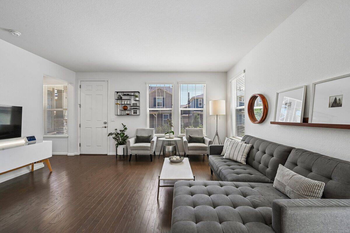 Living room with a gray sectional sofa, gallery wall, and dark hardwood floors, staged for showings