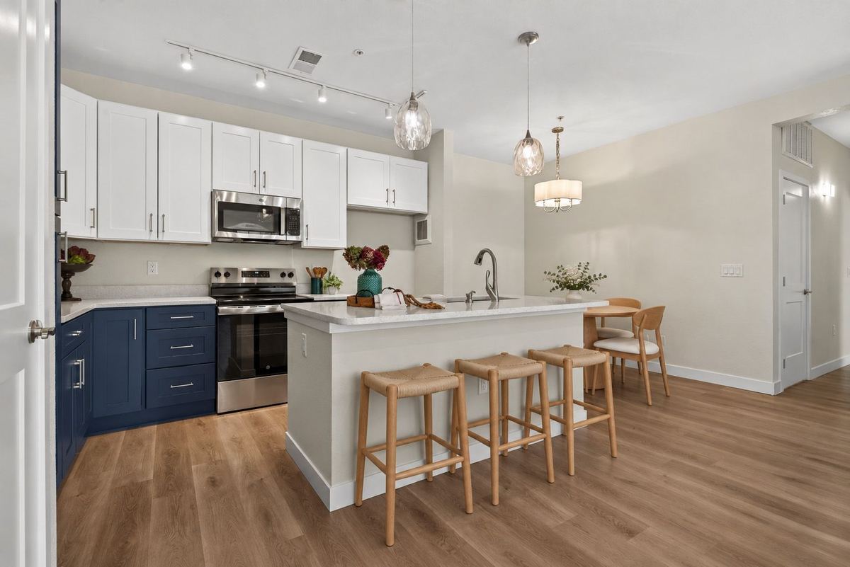 Kitchen with white upper cabinets, blue lower cabinets and a quartz island at Hunters Chase