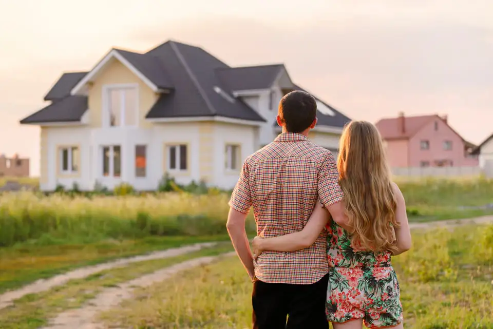 First-time buyers standing in front of their new home in Waltham, MA